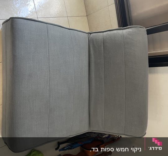 ספה אפורה על רצפה עם חפצים מתחתיה